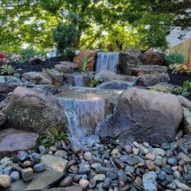 Pondless disappearing waterfall over natural stone into a gravel bed